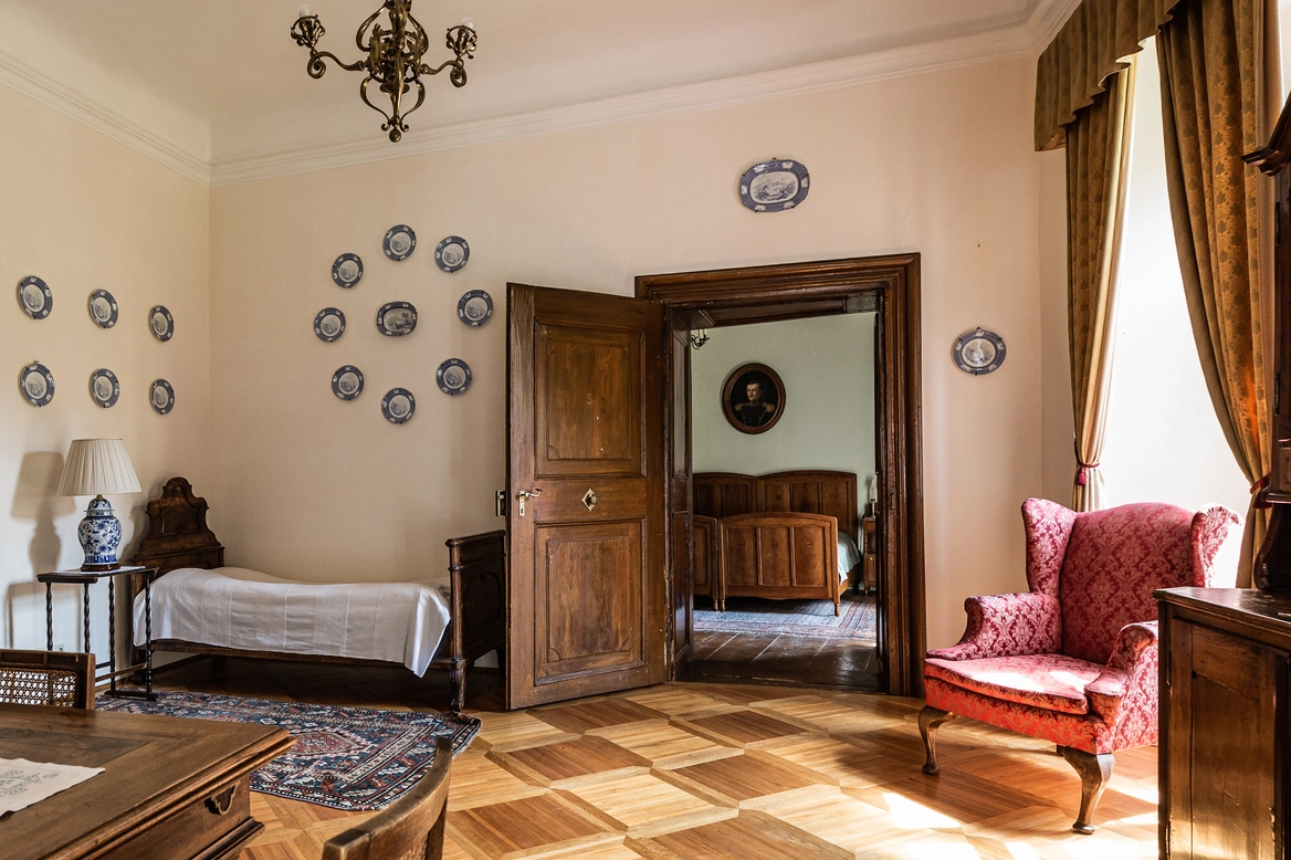 Ein Salon mit Tagebett, Blick auf das Schlafzimmer durch eine Holztüre