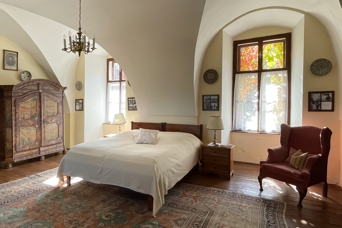 Ein Doppelbett mit schönem Stoffüberzug, dahinter Blick in den Burghof